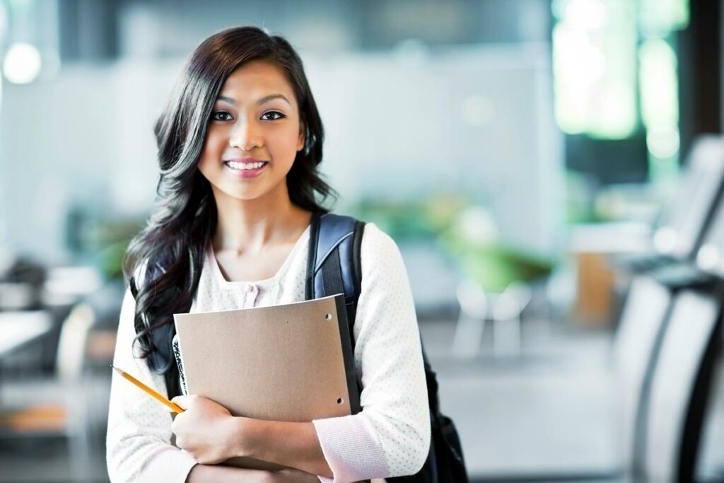 Female student wearing a backpack and holding a notebook.